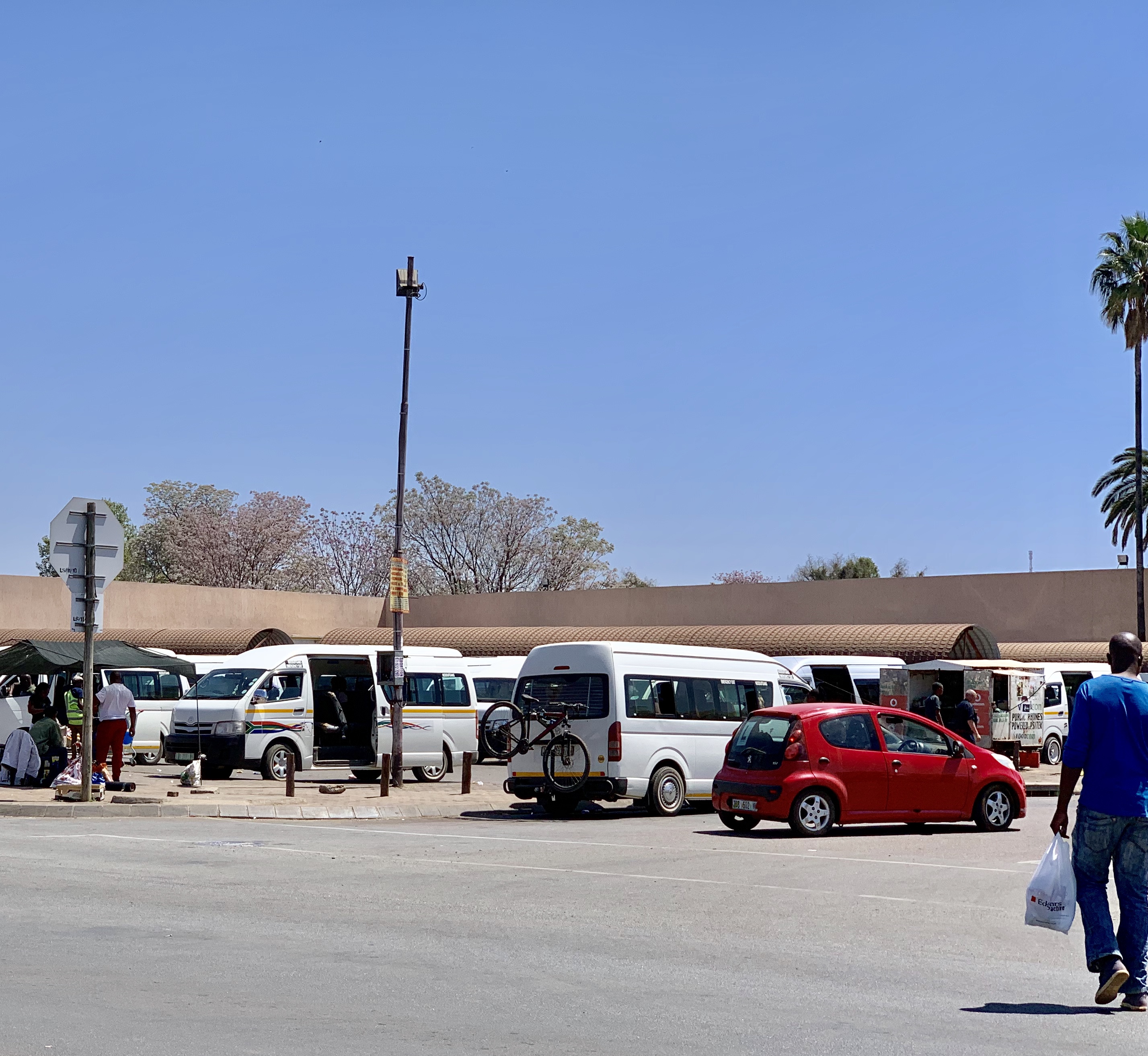 Photo of an intersection, with a pedestrian crossing. There is a taxi with a bike rack, and it is parked in the taxi rank.